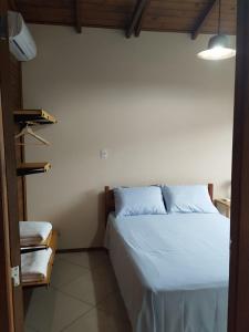 a bedroom with a bed with white sheets at Chalé da Val in Palhoça