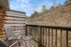 a deck with two chairs and a table and a fence at Rockwall Lodge - Close to Branson Strip in Branson