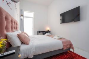een slaapkamer met een bed en een televisie aan de muur bij Primavera House in Faro