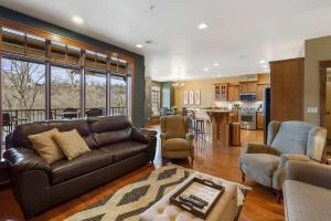 Una sala de estar con un sofá de cuero y una cocina. en Taneycomo Retreat - Lakefront Condo, en Branson