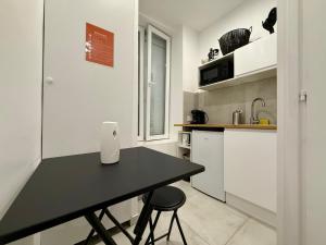 eine Küche mit einem schwarzen Tisch und 2 Hockern in der Unterkunft Cocon magic-Jacuzzi & Netflix in Villeurbanne