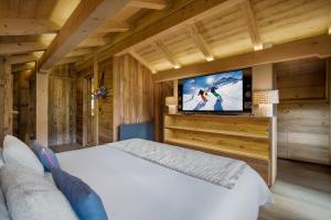 Un dormitorio con una cama y un televisor de pantalla plana. en Luxury Chalet Black Mountain - 4BR, Sleeps 10, Fireplace, Mountain Views & Garden - Megève, en Megève