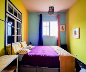 Un dormitorio con una cama con sábanas moradas y una ventana. en La Maison ZiaZen, en Porto da Cruz