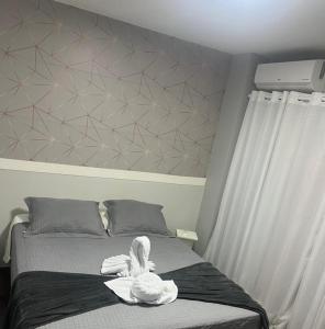 a swan sitting on top of a bed at Loft Centro - No Calçadão e em frente Parque das Águas in São Lourenço