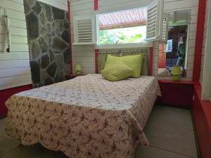 a bedroom with a bed with a blanket and a window at Chalet Plage et Kite in Le Vauclin