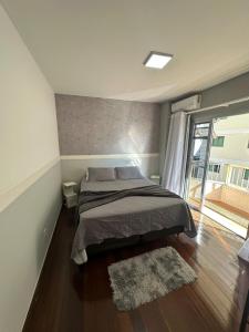 a bedroom with a bed and a large window at Loft Centro - No Calçadão e em frente Parque das Águas in São Lourenço