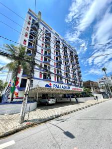 a large building with a palm tree in front of it at Skyblue Flat in São Vicente