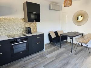 Una cocina con gabinetes negros y una mesa y sillas. en Villa T2 jacuzzi privé Les Charmettes, en La Ciotat