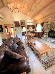 a living room with a leather couch and a fireplace at Tranquil Mountain Glamping Retreat: Stunning Log Cabin with a Hot Tub in Darby, MT in Peaks and Pines Park +3 photos