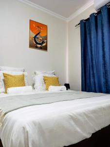 a bedroom with a large white bed with a blue curtain at Apartment near the University of Botswana in Gaborone