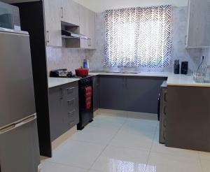 a kitchen with white counters and a window and a sink at Apartment near the University of Botswana in Gaborone +8 photos