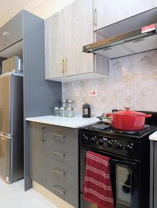 a kitchen with a stove with a red pot on it at Apartment near the University of Botswana in Gaborone