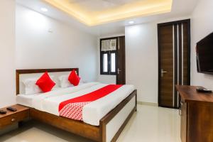 a bedroom with a bed with red pillows and a television at Super Hotel O Kazhakkoottam Near Technopark Phase 3 in Trivandrum
