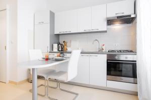 una cocina con armarios blancos y una mesa y sillas blancas. en Apartment Ribnjak en Zagreb