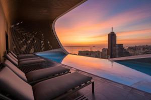 a rooftop pool with a view of a city at sunset at Luxury Apartment with Sea and Skyline Views St Julians in St Julian's