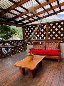 a wooden bed on a wooden deck with a table at Ankatu Hostel in El Bolsón