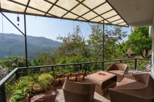 a balcony with chairs and tables and a view of the mountains at Murree Hills Executive 3 Bedroom Cottage with Scenic View in Murree