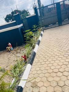 a person sitting on the ground next to a fence at Breathtaking Nest 2, cosy and spacious in Kampala