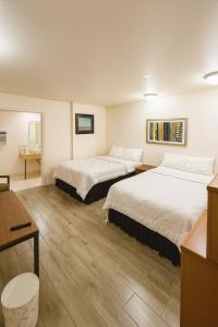 a hotel room with two beds and a desk at Sawmill Lodges Motel in Hennessey