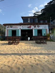 a building on the beach with tables and chairs at Ponta Da Barca in Praia Vermelha