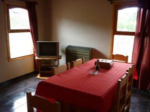 a dining room with a red table and a television at Nuevos Vientos in El Corcovado