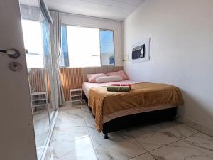 a small bedroom with a bed and a window at Apartment on the 3rd floor, 10 minutes from the beach, railway and bus station in Vila Velha