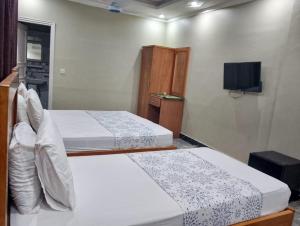 two beds in a room with a tv at Clifton BnB in Karachi
