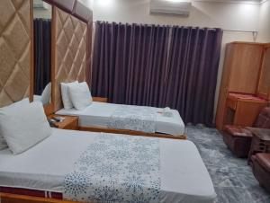 a hotel room with two beds and a chair at Clifton BnB in Karachi
