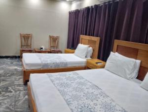 a hotel room with two beds and purple curtains at Clifton BnB in Karachi