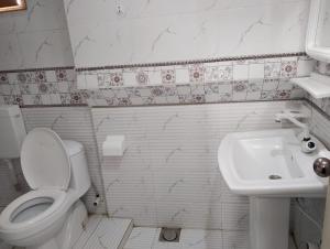 a white bathroom with a toilet and a sink at Clifton BnB in Karachi