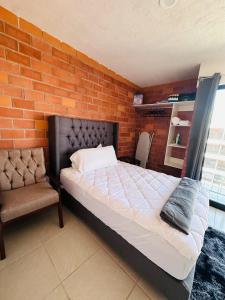 - un lit et une chaise dans une chambre dotée d'un mur en briques dans l'établissement Depa nuevo cerca del Akron, ITESO, Periferico Sur, à Guadalajara