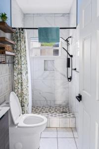 a white bathroom with a toilet and a shower at Garden Apartment in Trinity