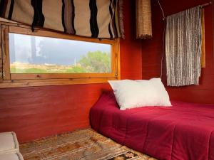 une chambre rouge avec un lit et une fenêtre dans l'établissement Bed0Bled Cabanes & Holiday homes, à Sidi Kaouki 42 autres photos