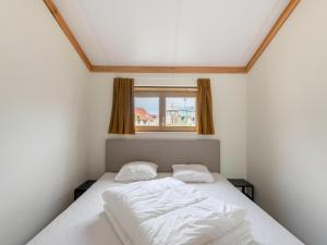 a bedroom with a bed with white sheets and a window at Westhinder I H19 in Koksijde
