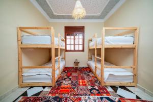 Habitación con 3 literas y lámpara de araña. en Lumir Surf House, en Tamraght Ouzdar 8 fotos más