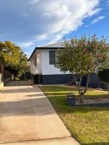 a house with a tree next to a sidewalk at Gravity Stayz in Batehaven