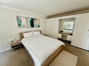 a bedroom with a large white bed and a window at Gravity Stayz in Batehaven