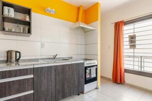 a kitchen with orange and white walls and a sink at Departamentos Brown -WiFi 100 MB - Cochera - Parrilla - Aire - TV Cable in San Rafael +34 photos