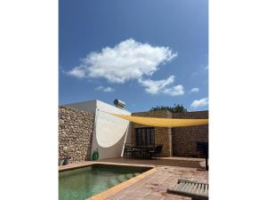 a house with a swimming pool and a yellow canopy at Stone house with private pool in Agua Amarga in Los Cerrillos