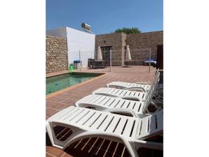 a row of white lounge chairs next to a pool at Stone house with private pool in Agua Amarga in Los Cerrillos