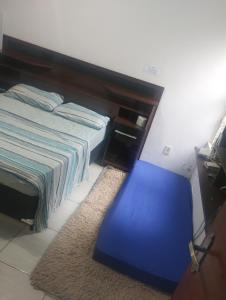 une chambre avec un lit et un tabouret bleu dans l'établissement Elaine, à Cachoeira Paulista