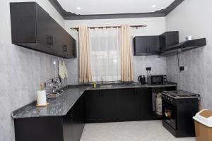 a kitchen with black cabinets and a counter top at JH Luxury Suites in Kampala