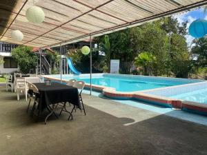 a swimming pool with a table and chairs next to a pool at Hotel & Restaurante Tabacones in Guácimo