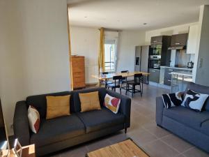 a living room with a couch and a kitchen at Agréable chambre in Prévessin