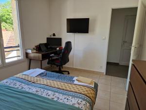 a bedroom with a bed and a desk with a computer at Agréable chambre in Prévessin