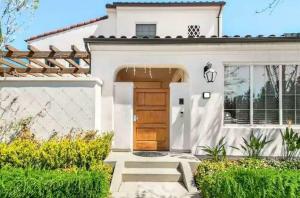 a white house with a brown door and some bushes at Private suite downstairs in Irvine
