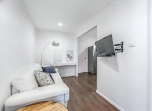 a white living room with a white couch and a tv at Cosy 2BR Paddington Home with Parking in Brisbane