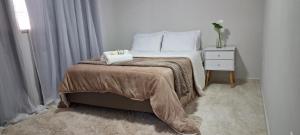 a bedroom with a bed and a night stand and a window at Casa Bello Monte in Venda Nova do Imigrante