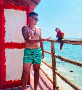 プラヤ・ブランカにあるMachu Picchu -Barúのフェンスの上に立っている男性と彼の後ろにいるオウム