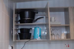 a kitchen cabinet with dishes and pots and pans at Urban Nest suites in Kisii